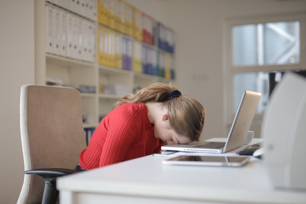 femme fatiguée portant la tête contre son ordinateur pour démontrer sa fatigue émotionnelle ou hivernale